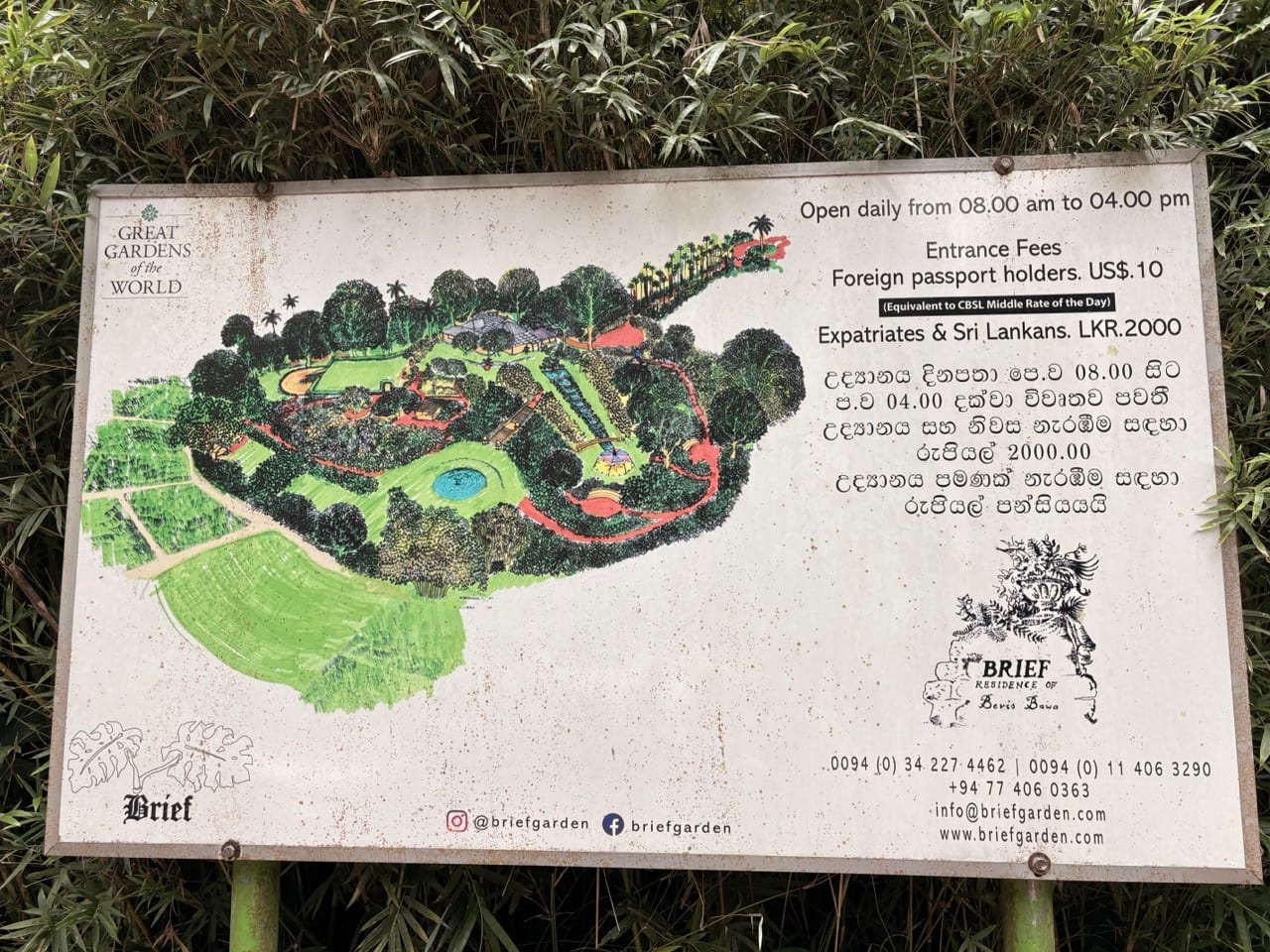 The painted board at the garden gate showing a hand-drawn map of the grounds beside the opening hours and entrance fees