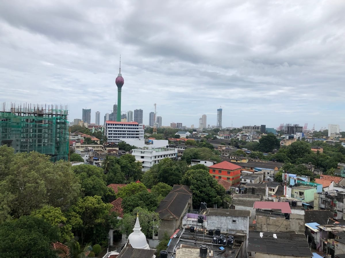 The Colombo skyline with the Lotus Tower rising above rooftops and a small white stupa in the foreground