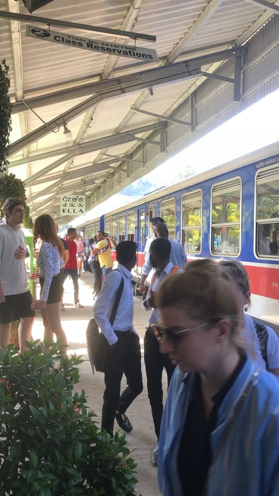 Blue train standing at Ella railway station platform with passengers waiting alongside