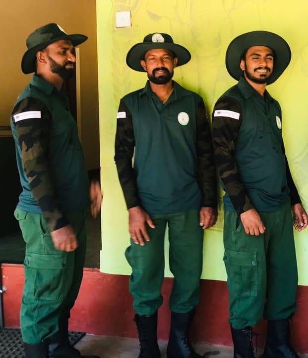 Three Department of Wildlife Conservation rangers in green uniform standing together